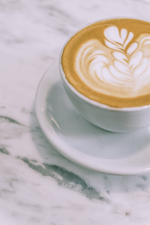 Free From above cup of appetizing hot foamy cappuccino with latte art placed on marble table in cafe Stock Photo