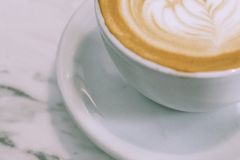 From above cup of appetizing hot foamy cappuccino with latte art placed on marble table in cafe