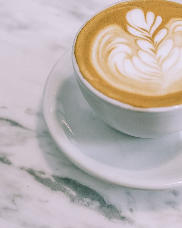A cappuccino with rosetta latte art on a marble counter