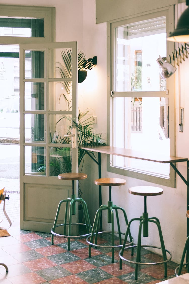 Interior Of Stylish Cafe With Wooden Counter And Stools Placed Near Window