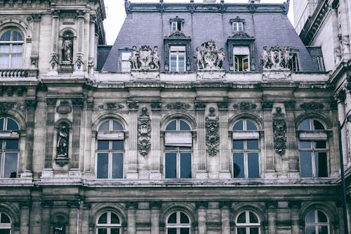 Exterior of old elegant building with sculptures and mansard windows built in renaissance architectural style and located in Paris