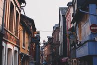 Narrow alley between typical buildings with colorful facade and brick walls located on street in town against cloudless sky in neighborhood