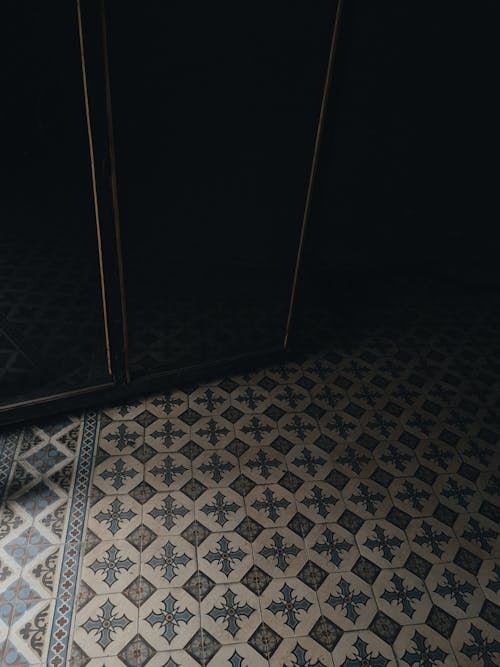 Tiles with bright ornamental elements and creative patterns on floor near wall in light spacious corridor of modern apartment building