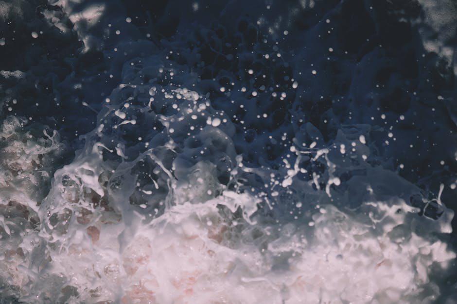 Close-up view of a powerful ocean wave crashing with white foam and water droplets.