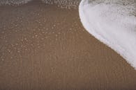 Sandy beach with foamy ocean water in daylight