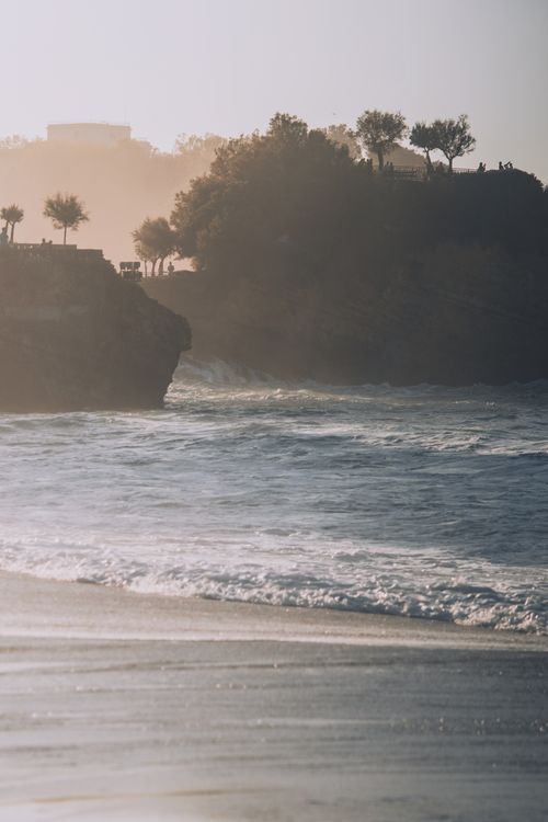 Free Coast near foamy sea and mounts with trees under misty sky on summer day Stock Photo