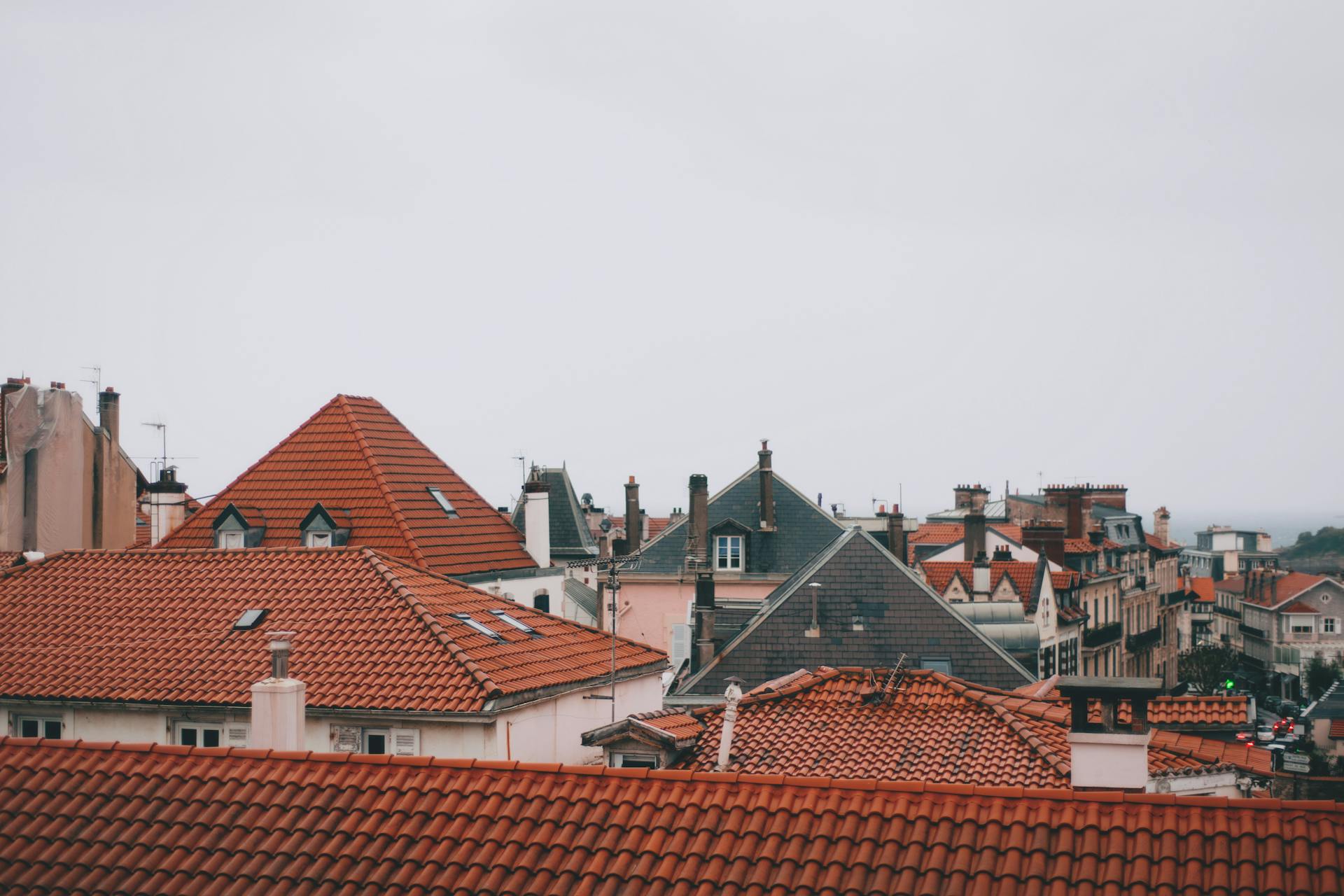 Old dwelling building roofs with ribbed tiles and attic windows in city in daylight