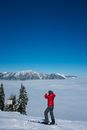在无云的天空下，一名身着外套、脚踏滑雪板的游客侧影，正探索着雪山