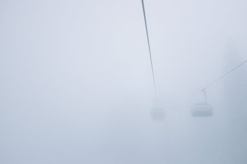 From below of cabins on ropeway under misty sky in cold weather in daylight