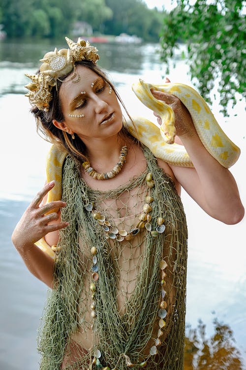 Fashionable young pregnant woman with reticulated python on shoulders