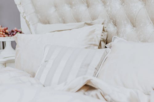 Free Soft comfortable bed with white pillows blanket and headboard in cozy bedroom in morning Stock Photo