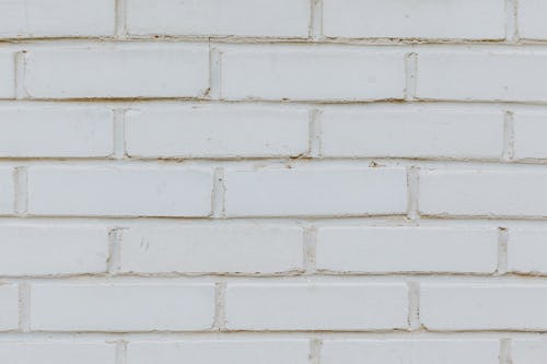Textured background of imitation brick on white wall covered with plaster on building
