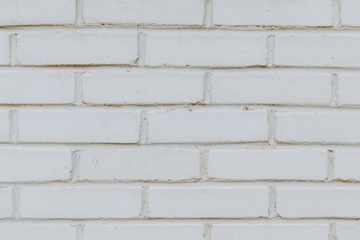 Textured background of imitation brick on white wall covered with plaster on building