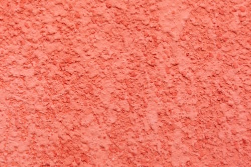 Textured surface of bright wall covered with decorative stucco of bright coral color