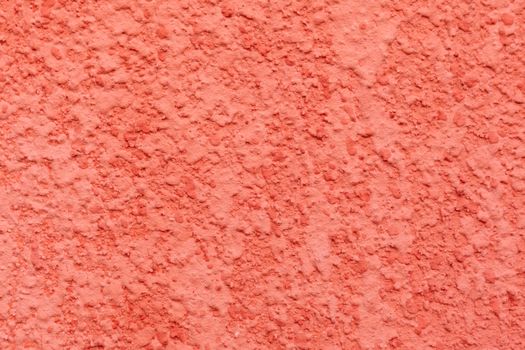 Textured surface of bright wall covered with decorative stucco of bright coral color