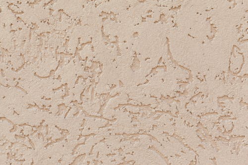 Background of cracked plaster surface with rough texture of light beige color on wall