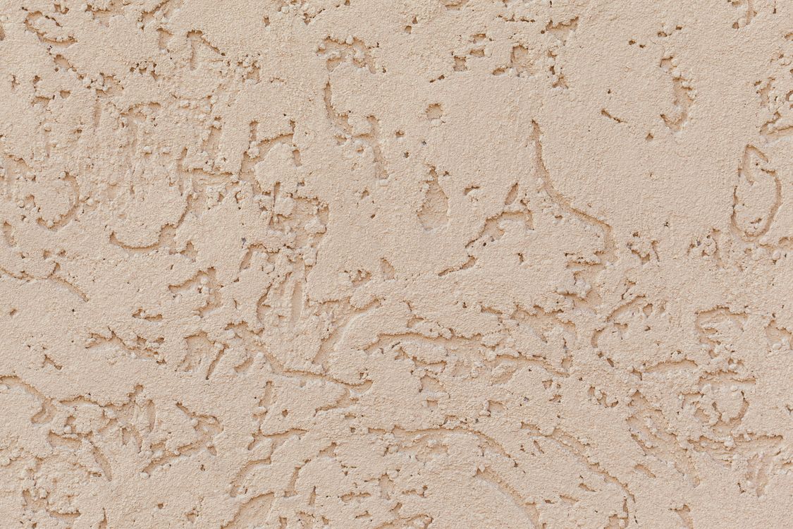 Close view of a textured beige plaster wall with fine surface cracks