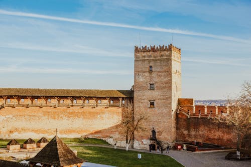 Free High angle of people walking along shabby aged stone fortress with bricked walls and tower Stock Photo