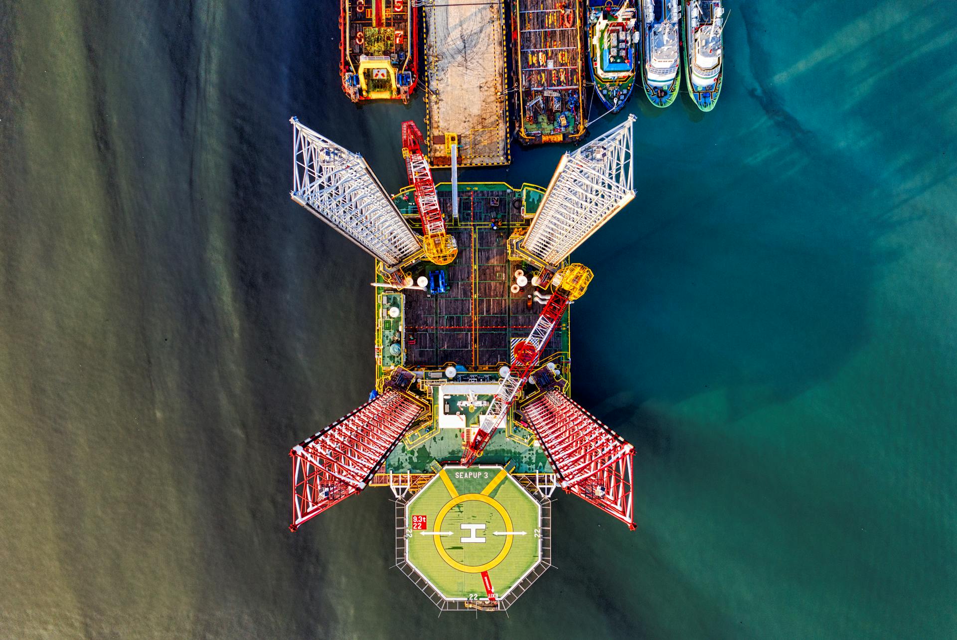 Stunning aerial view of a vibrant offshore oil rig with crane and helipad in Jakarta's waters.