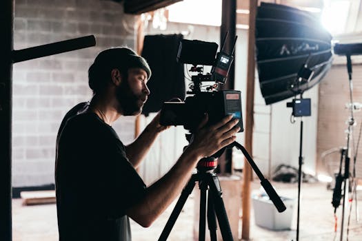 Cinematographer adjusting camera on an indoor film set with professional lighting.