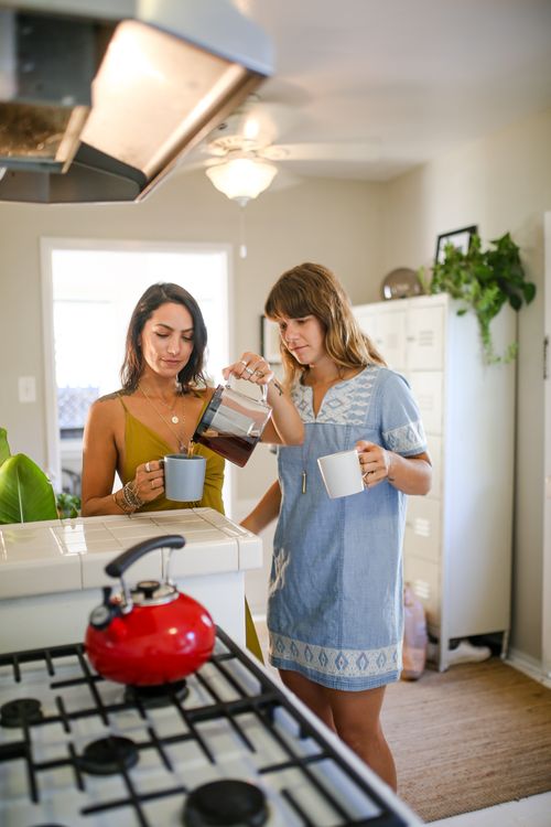 Free Two women enjoying a morning coffee together in a bright and cozy kitchen. Stock Photo