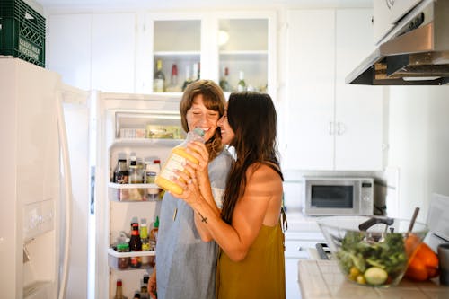 Happy Couple standing in front of a Refrigerator 