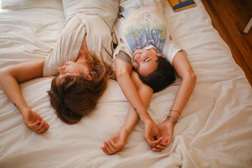 Free Two women lying on a bed, enjoying leisure time and relaxation indoors. Stock Photo