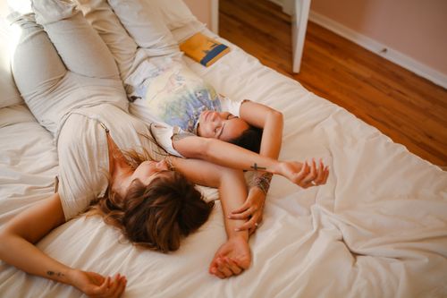 Free Two women lying on a bed, relaxed and enjoying leisure time in a cozy bedroom. Stock Photo