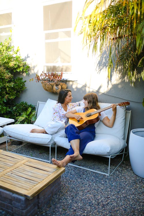 Donna In Maglietta Gialla Che Gioca Chitarra Che Si Siede Sul Sofà Bianco