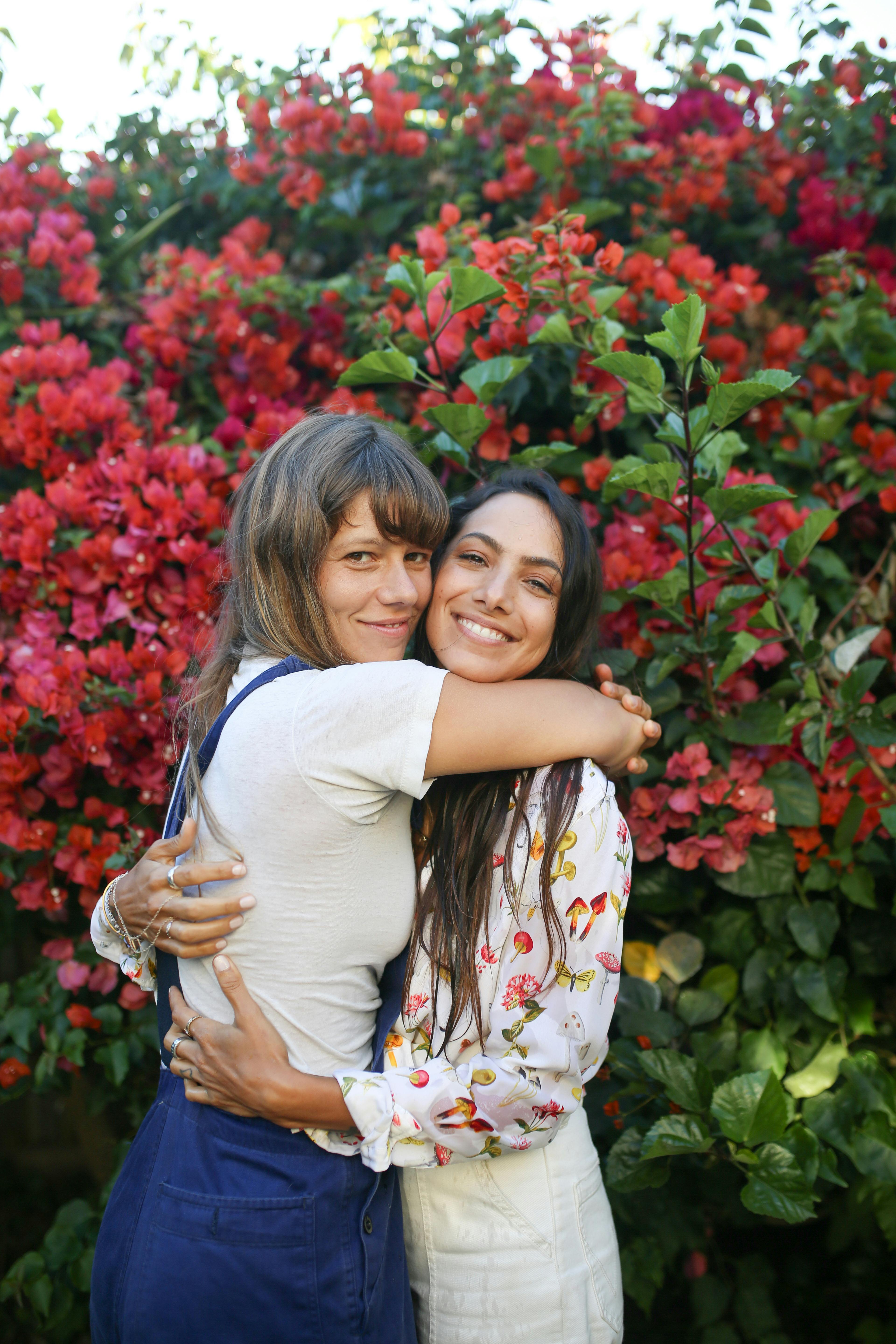 woman in white shirt hugging girl in yellow and white floral dress