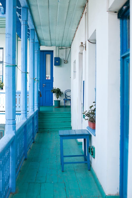 Balcony of residential building with blue wooden fence and potted plants on windowsill