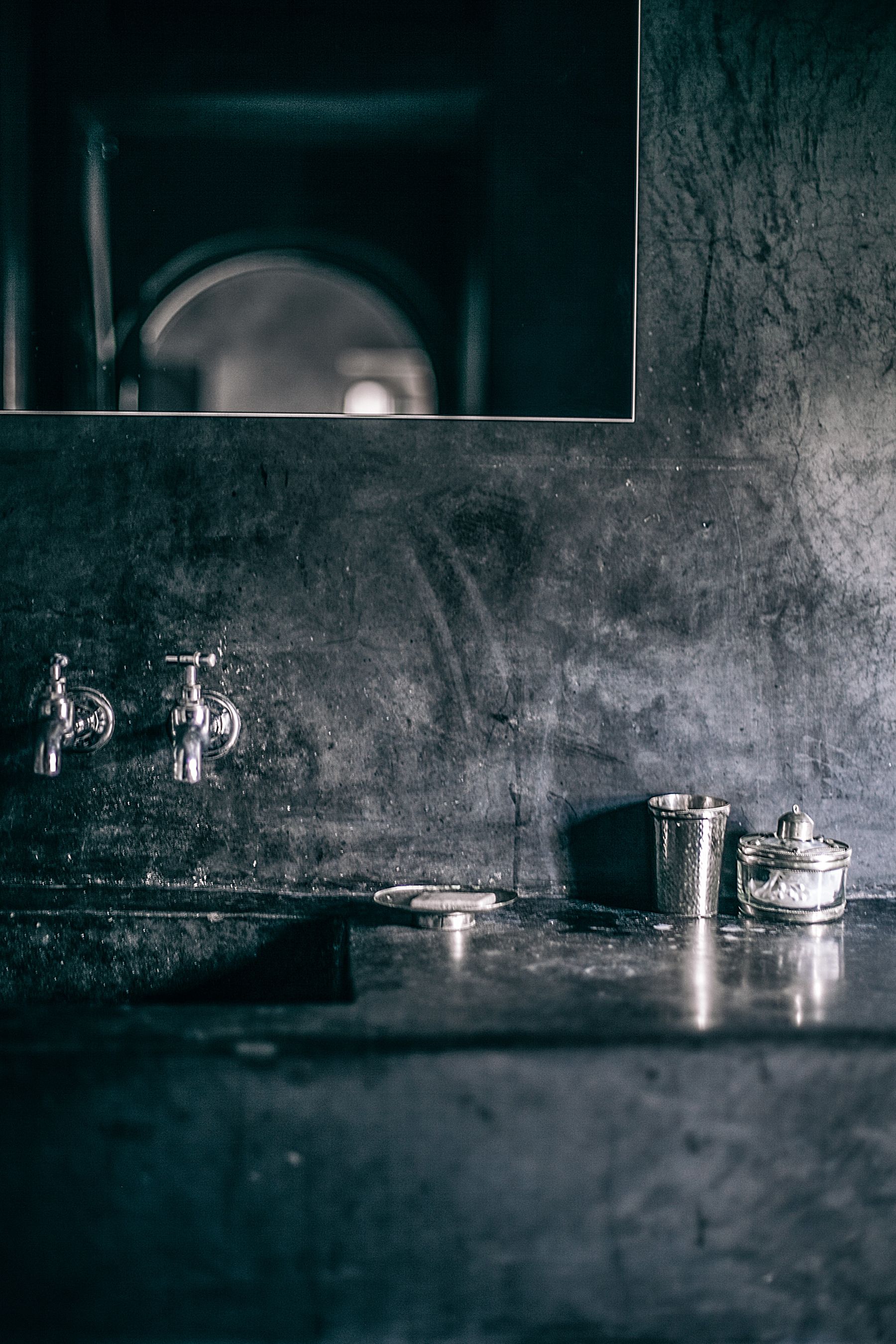Dark sink area with a black basin, black tap and a simple mirror