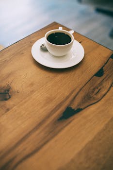 A warm, inviting coffee cup on a rustic wooden table in a cozy café setting.
