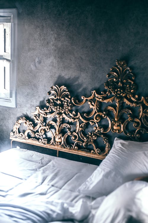 Free From above of comfortable unmade bed with white sheet and blanket and decorative carved elements on headboard Stock Photo