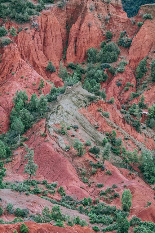 From above of steep rocky range with uneven ridges covered with green plants in highland