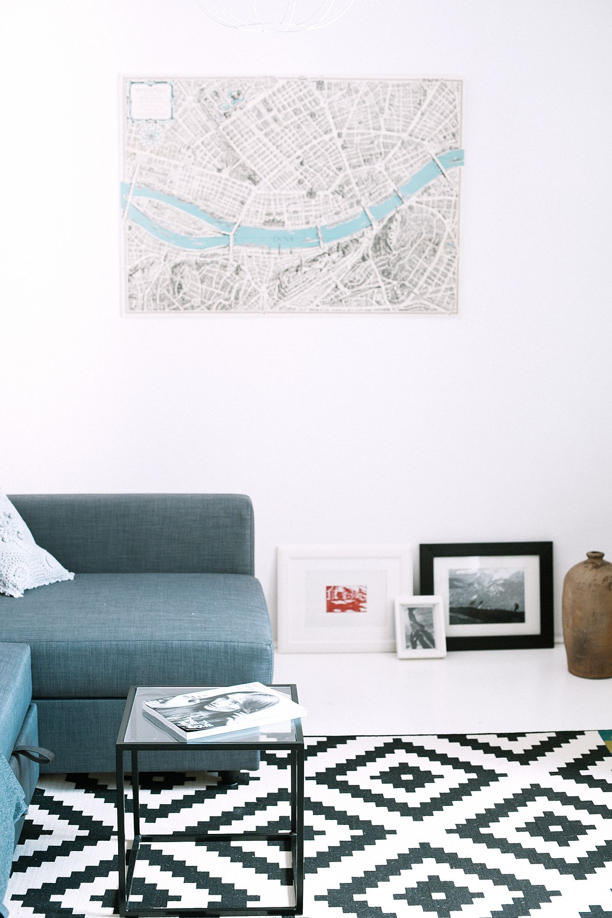 Bold black and white geometric rug with a teal sofa in a bright living room
