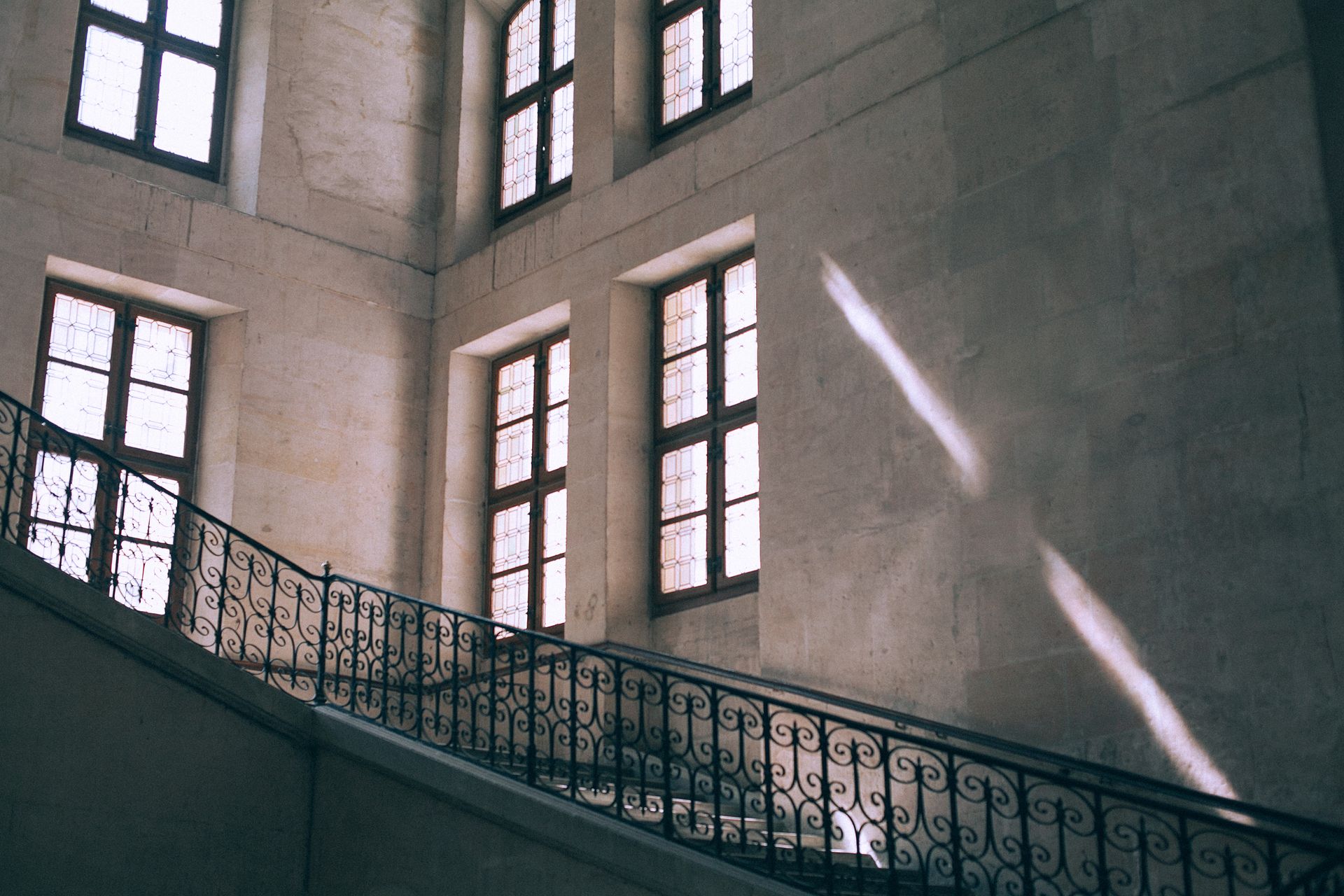 From below of staircase with decorative metal railing in aged multistory masonry house in sunlight