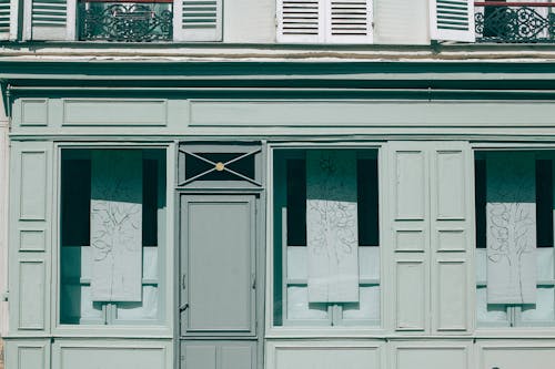 Textured background of aged building facade with ribbed wooden shutters and ornamental fences in town