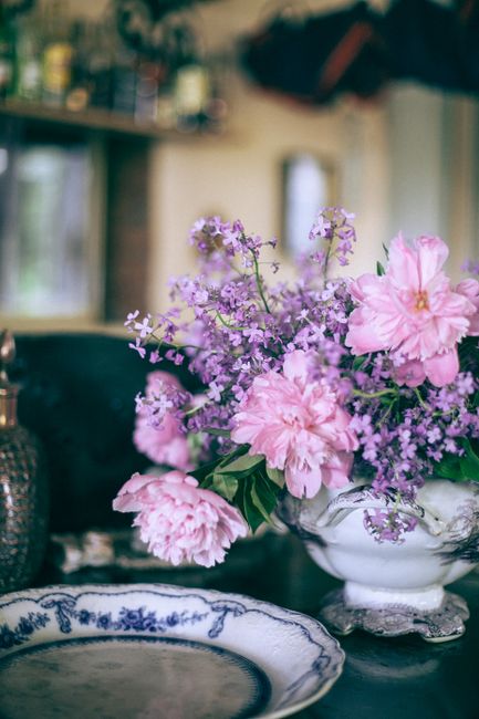 Colorful flower bouquet with pleasant aroma and gentle petals in ceramic vase near plate in house