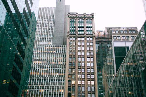 Free Low angle of high modern building exteriors with shiny front walls under white sky in town Stock Photo