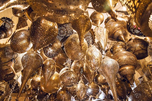 From below of assorted ornamental Moroccan lamps with tiny holes on shiny surface in local market