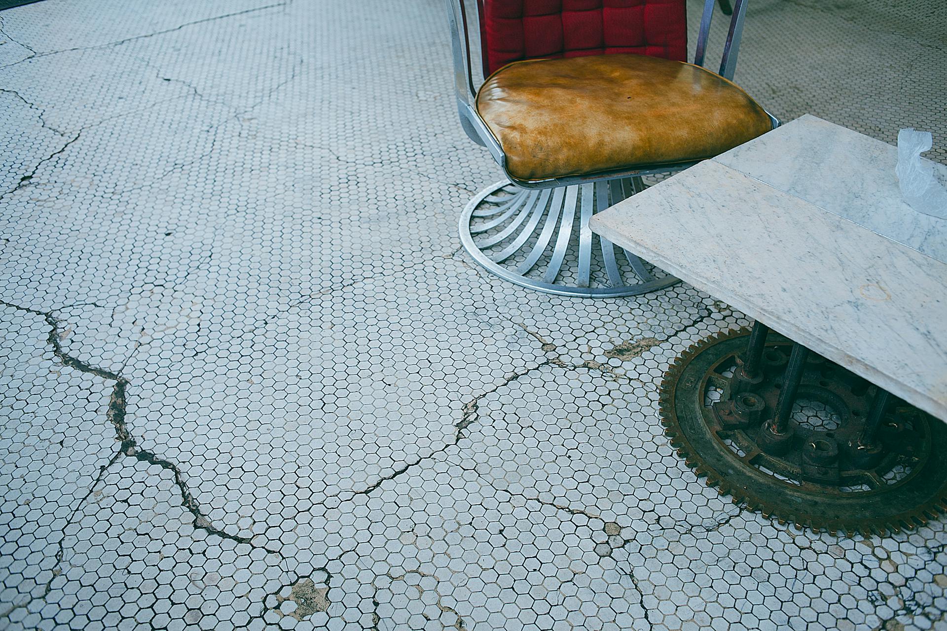 Old armchair near table on floor with cracks