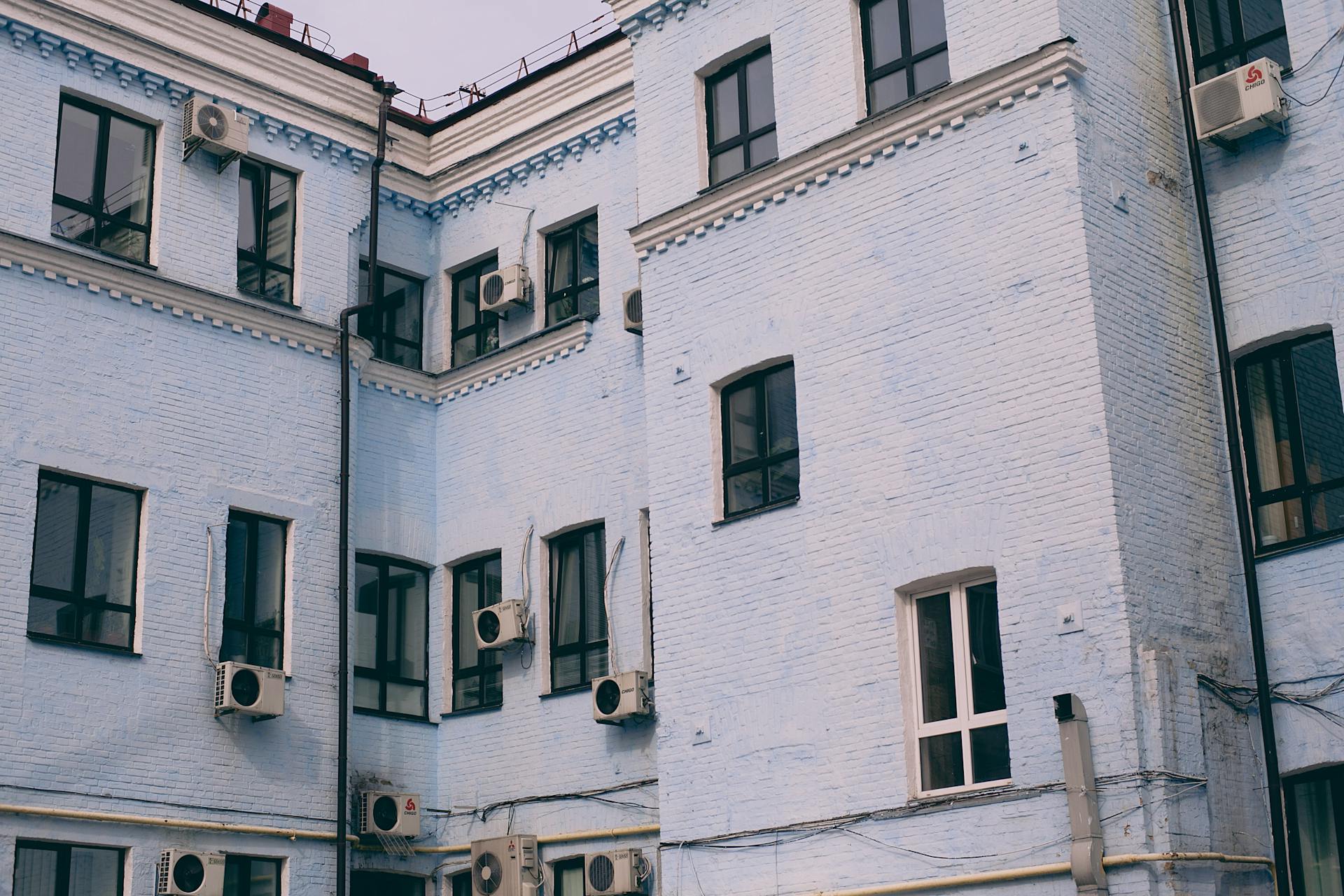 Close-up of a blue brick urban residential building exterior with air conditioning units.