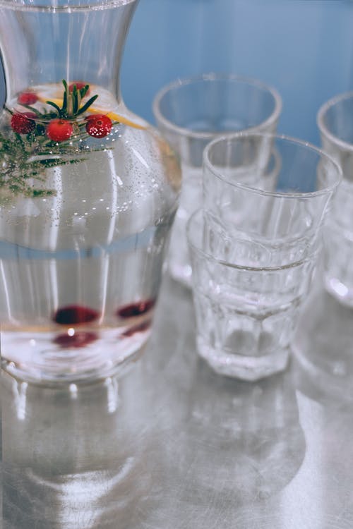 Lemonade with fresh cherries near glassware on table