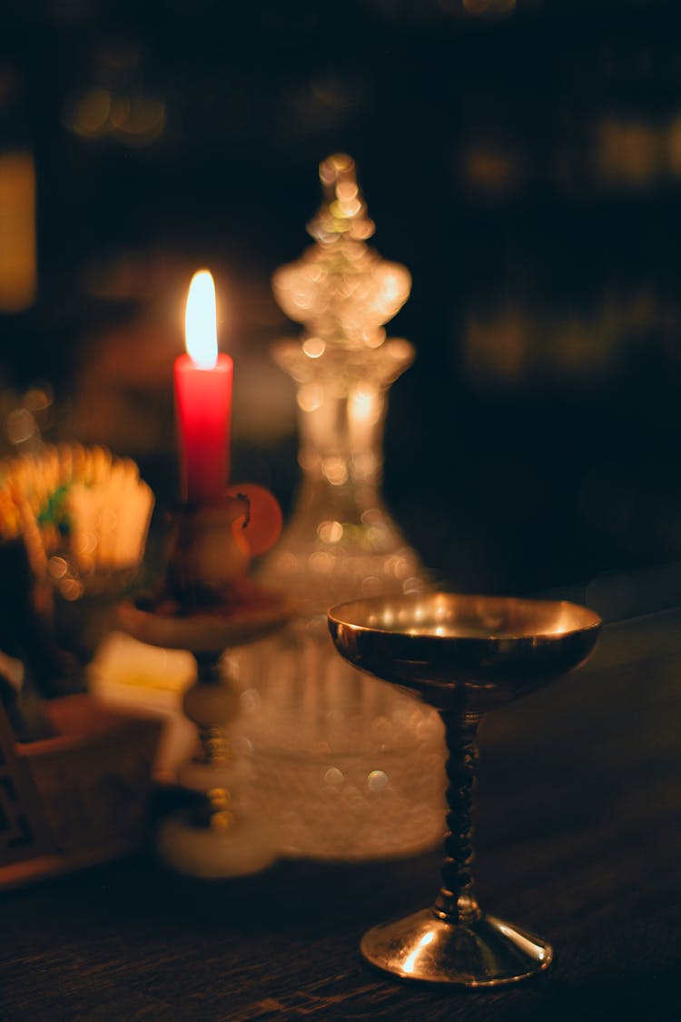 Burning Candle Near Metal Bowl And Carafe In Church