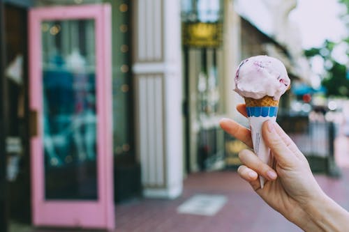 Урожай человек показывает вкусное мороженое на улице