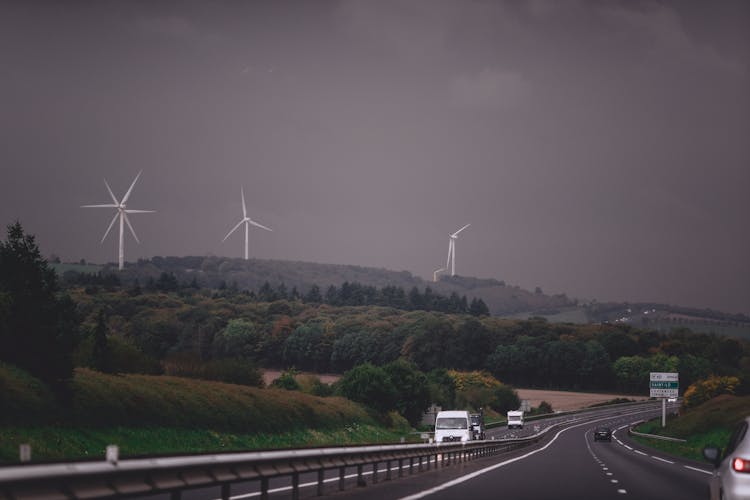 Roadway Through Green Field With Wind Farm