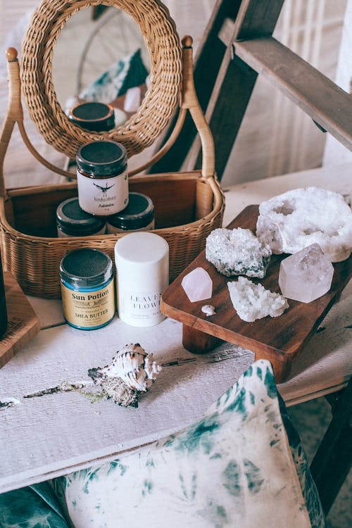 Free From above of beauty jars in wicker basket reflecting in mirror near sea shell and collection of crystals Stock Photo