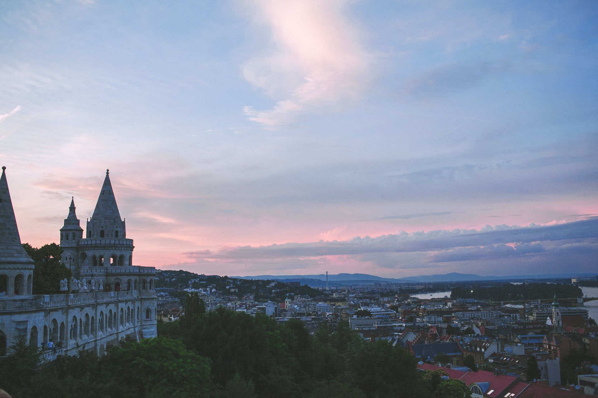 Aged masonry building facade near trees under sky with clouds in Hungary at sunset