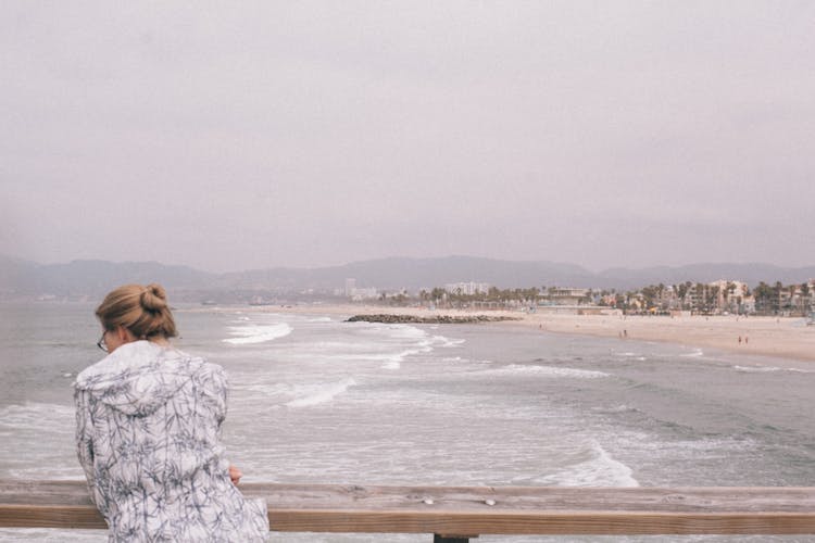 Unrecognizable Tourist Contemplating Stormy Sea From Embankment